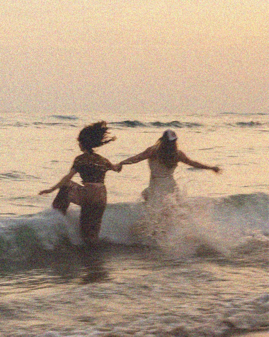 Two friends in the ocean at sunset